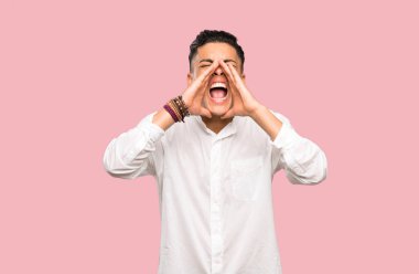 Genç adam bağırıyor ve renkli arka plan üzerinde bir şey ilan