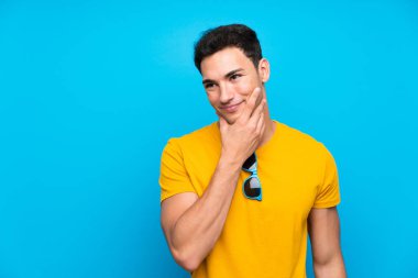 Mavi arka plan üzerinde yakışıklı adam bir fikir düşünme