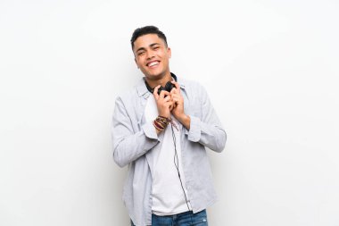 Kulaklıklı izole beyaz duvar üzerinde genç adam