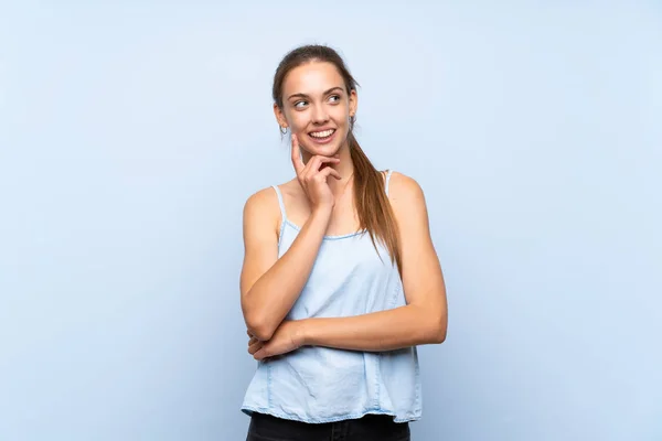 Jovem Mulher Sobre Fundo Azul Isolado Pensando Uma Ideia Enquanto — Fotografia de Stock