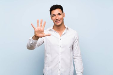 Mavi duvar üzerinde yakışıklı adam parmakları ile beş sayma
