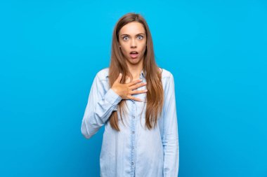 İzole mavi arka plan üzerinde genç kadın sürpriz ve doğru bakarken şok