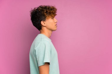 Izole mor duvar üzerinde genç afro-amerikan adam kollarını çapraz ve yan görünümlü tutmak