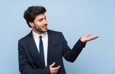 İzole mavi duvar üzerinde işadamı gelmeye davet için elleri yana uzatıyor