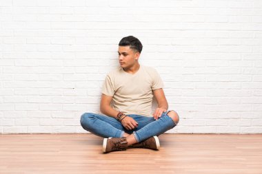 Yerde oturan genç adam yan bakıyor