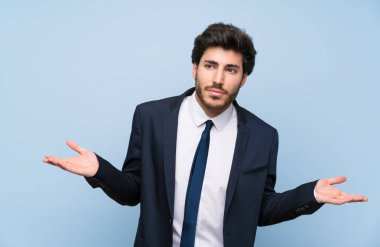 El kaldırırken şüpheleri olan izole mavi duvar üzerinde işadamı