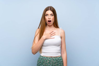 İzole mavi arka plan üzerinde genç kadın sürpriz ve doğru bakarken şok