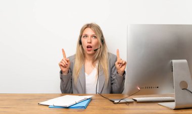 İşaret parmağıyla işaret eden kulaklıkla çalışan genç kadın harika bir fikir