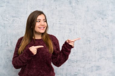 Genç kız yana parmak işaret grunge duvar üzerinde