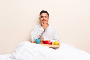 Yatakta gülerek kahvaltı alan genç adam