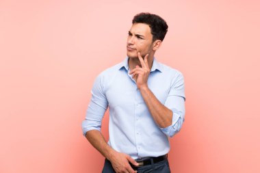 Yakışıklı adam pembe arka plan üzerinde bir fikir düşünürken yukarı bakarken