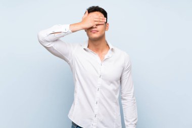 Mavi duvarın üzerinde gözleri elleriyle kaplayan yakışıklı bir adam. Bir şey görmek istemiyorum