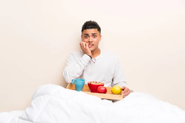 Young man having breakfast in bed nervous and scared