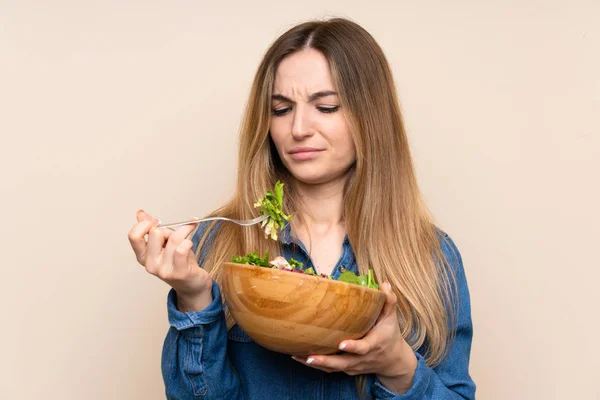 Young woman with salad over isolated background