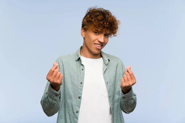 Young African American Man Isolated Blue Wall Making Money Gesture — Stock Photo, Image