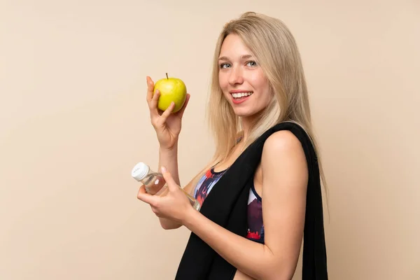 Fiatal szőke sport nő egy almát és egy üveg vizet — Stock Fotó