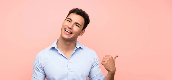 Knappe Man Roze Achtergrond Wijzend Naar Zijkant Een Product Presenteren — Stockfoto