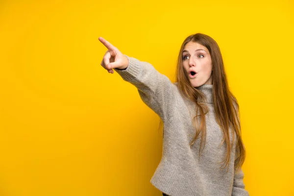 Sarı Arka Plan Üzerinde Uzun Saçlı Genç Kadın Uzak Işaret — Stok fotoğraf
