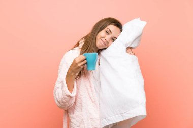 Bir fincan kahve tutan pembe duvar üzerinde sabahlık mutlu genç kadın