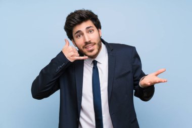 Izole mavi duvar üzerinde Işadamı telefon jest yapma ve şüphe
