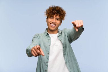 Izole mavi duvar üzerinde genç afrikalı Amerikalı adam gülümserken size parmak