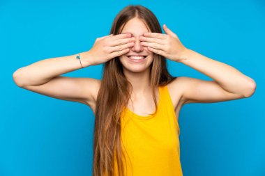 Gözleri elleriyle kaplayan izole mavi duvar üzerinde uzun saçlı genç kadın