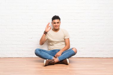 Genç adam parmakları ile ok işareti gösteren katta oturan