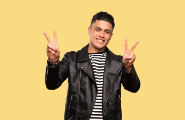 İzole arka plan üzerinde iki eliyle zafer işareti gösteren genç adam