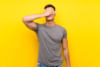 Gözleri elleriyle kaplayan izole sarı duvarın üzerindeki yakışıklı adam. Bir şey görmek istemiyorum