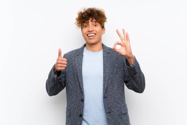 Izole beyaz duvar üzerinde moda afro-amerikan adam ok işareti ve başparmak kadar jest gösteren