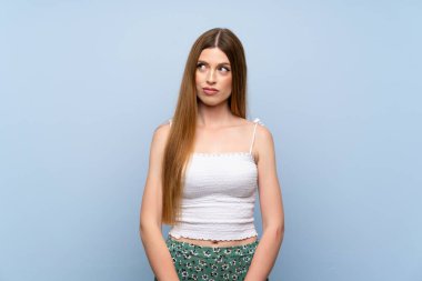 Soyutlanmış mavi arka planda genç bir kadın şüpheli hareketler yapıyor.