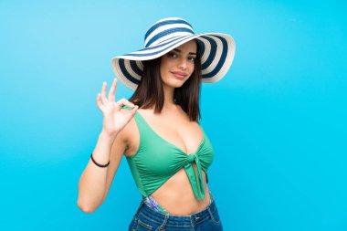 Yaz tatillerinde mayo giyen genç kadın parmaklarıyla ok işareti gösteriyor