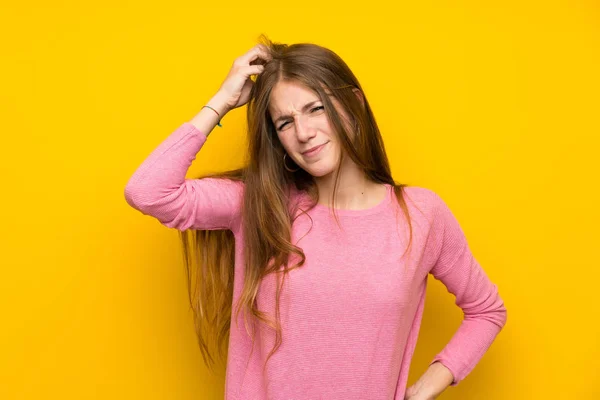 頭を引っ掻きながら疑問を持つ孤立した黄色の壁の上に長い髪を持つ若い女性 — ストック写真