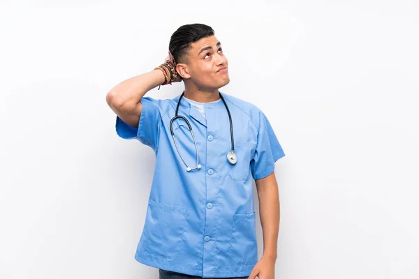 Mladý Chirurg Doktor Muž Nad Izolovanou Bílou Stěnou Pochybnosti Plete — Stock fotografie