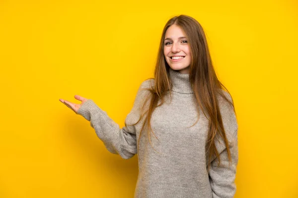 手のひらにコピースペースの想像を保持する黄色の背景の上に長い髪を持つ若い女性 — ストック写真