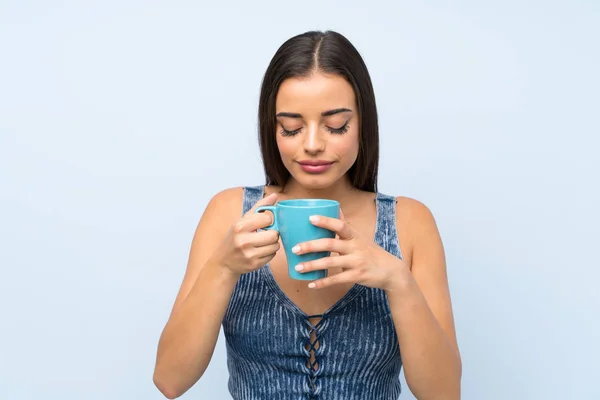 Mujer Joven Sobre Aislada Pared Azul Sosteniendo Taza Café Caliente —  Fotos de Stock