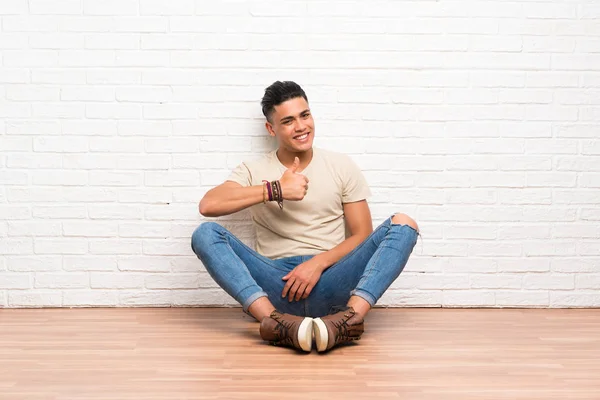Genç Adam Yerde Oturuyor Baş Parmak Işareti Yapıyor — Stok fotoğraf