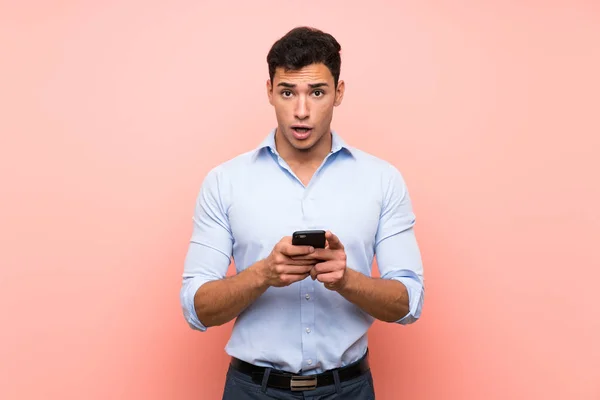 Hombre Guapo Sobre Fondo Rosa Sorprendido Enviando Mensaje —  Fotos de Stock