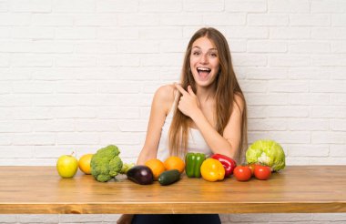 Birçok sebze ile genç kadın yan parmak işaret