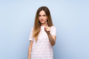Izole mavi arka plan üzerinde genç kadın sinirli ve ön işaret