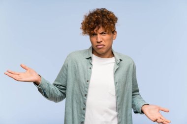 Izole mavi duvar üzerinde genç afrikalı Amerikalı adam bir şey anlamak için mutsuz