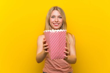 Pembe duvar üzerinde patlamış mısır ile genç kadın