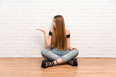 Genç kadın avuç üzerinde hayali copyspace tutarak katta oturan