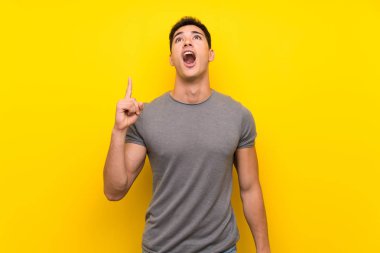 Izole sarı duvar üzerinde Yakışıklı adam işaret ve şaşırttı