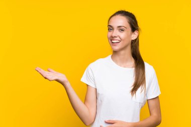 Avuç içinde copyspace hayali tutan izole sarı arka plan üzerinde genç kadın