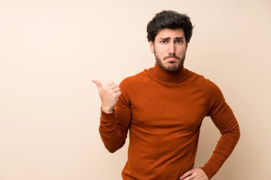 Izole duvar üzerinde Yakışıklı mutsuz ve yan işaret