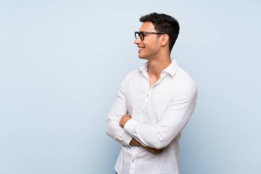Gözlük ve gülümseyen mavi duvar üzerinde Yakışıklı adam