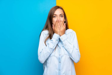 Sürpriz yüz ifadesi ile renkli arka plan üzerinde genç kadın