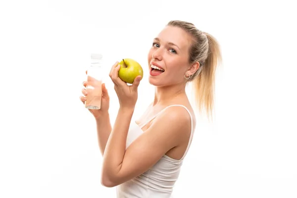 Ung blond kvinna med ett äpple och en flaska vatten — Stockfoto