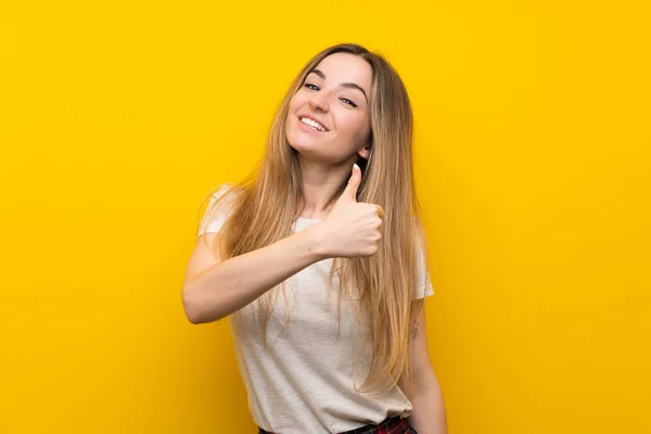 年轻女子在孤立的黄色墙壁上竖起大拇指手势 — 图库照片